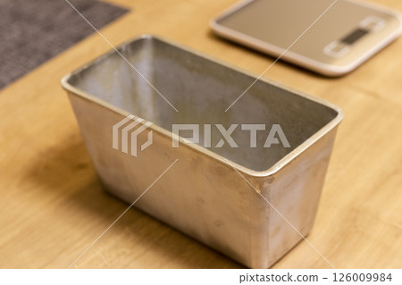 Small electronic scale on the kitchen counter top beside with the bread loaf pan Small electronic scale on the kitchen counter top beside with the bread loaf pan 126009984