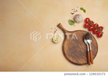 Food background with wooden cutting board, tomatoes, garlic, fresh basil and spices on light beige table, space for text 126010172