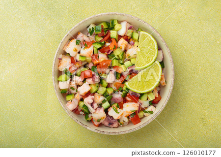 Peruvian seafood ceviche with shrimps, octopus, tomatoes, cucumber, and parsley in a bowl served with lime top view Peruvian seafood ceviche with shrimps, octopus, tomatoes, cucumber, and parsley in a bowl served with lime top view 126010177
