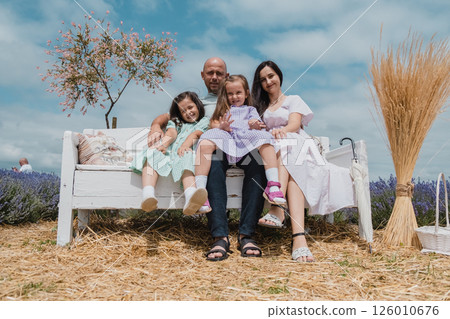 A happy family resting on a retro bench. 126010676