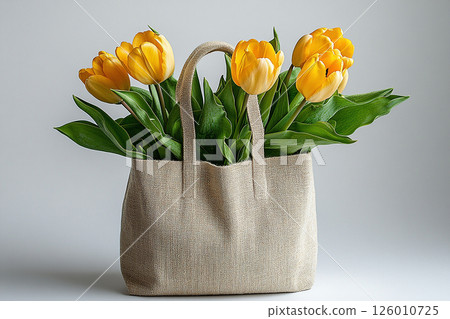 Reusable shopping bag made of fabric with a bouquet of yellow tulips on a white background. Reusable shopping bag made of fabric with a bouquet of yellow tulips on a white background. 126010725