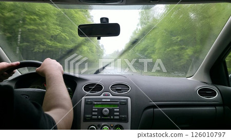 Driving in heavy rain. Interior view from the driver's seat. Wet windshield, blurred road and trees. Focus on the journey. Travel, transportation concept. Driving in heavy rain. Interior view from the driver's seat. Wet windshield, blurred road and trees. Focus on the journey. Travel, transportation concept. 126010797