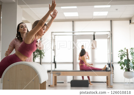 A trainer adjusts woman on a Ladder Barrel. A trainer adjusts woman on a Ladder Barrel. 126010818