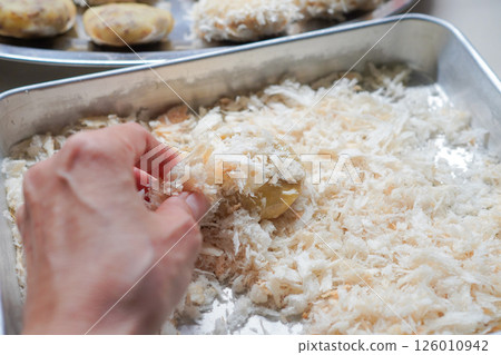 A woman's hands making homemade croquettes using raw breadcrumbs 126010942