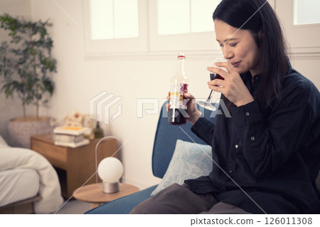 A woman in her 40s drinking wine at home during the day A woman in her 40s drinking wine at home during the day 126011308