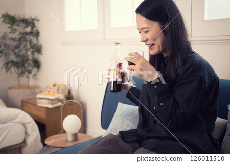 A woman in her 40s drinking wine at home during the day A woman in her 40s drinking wine at home during the day 126011510