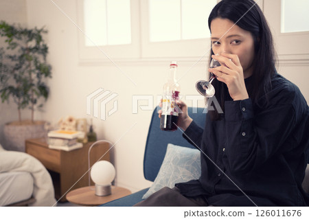 A woman in her 40s drinking wine at home during the day A woman in her 40s drinking wine at home during the day 126011676