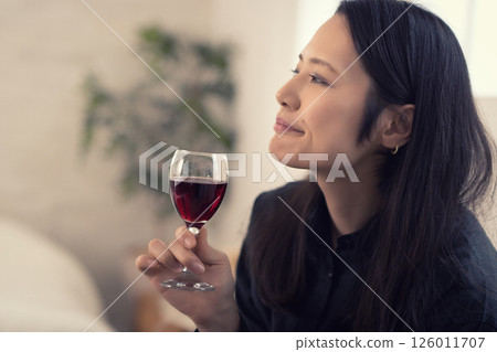 Middle-aged woman drinking wine at home during the day Middle-aged woman drinking wine at home during the day 126011707