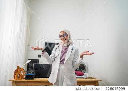 A smiling female doctor is present in an office setting, equipped with a stethoscope 126012099