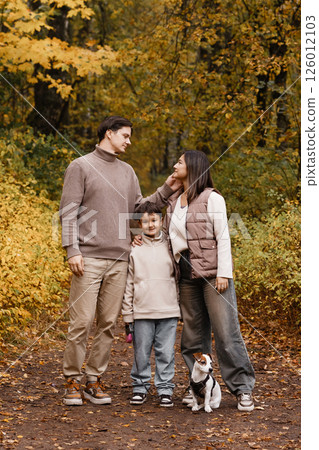 Happy family of three with dog in autumn park 126012103
