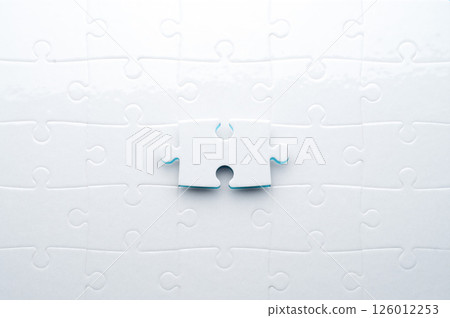 Concept for problem-solving, teamwork, solutions, or missing connections. White jigsaw puzzle on a vibrant blue background with one missing piece. Minimalist composition with copy space. 126012253
