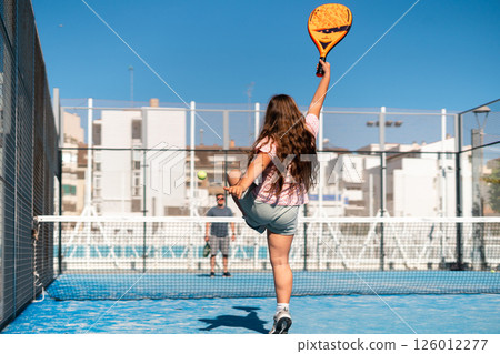 Young woman hitting a powerful shot on a sunny tennis court. Young woman hitting a powerful shot on a sunny tennis court. 126012277