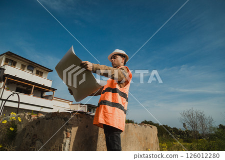 Architect On The Construction Site While Analyzing The Project Map  126012280