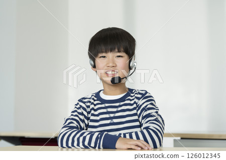 一名四年級男孩戴著耳機 一名四年級男孩戴著耳機 126012345