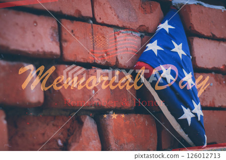 Close-up of a folded American flag on a red brick wall with the words Memorial Day Remembers and Honor. A symbol of remembrance and national pride. Close-up of a folded American flag on a red brick wall with the words Memorial Day Remembers and Honor. A symbol of remembrance and national pride. 126012713