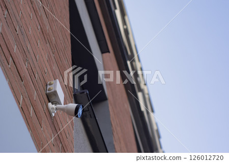 CCTV camera on the wall of a residential building for surveillance and protection in an urban area. 126012720