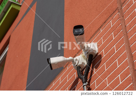 CCTV camera on the wall of a residential building for surveillance and protection in an urban area. CCTV camera on the wall of a residential building for surveillance and protection in an urban area. 126012722