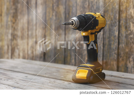 Yellow Cordless power drill on wooden surface for construction, DIY, and home repair projects. Yellow Cordless power drill on wooden surface for construction, DIY, and home repair projects. 126012767