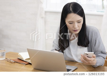 A beautiful middle-aged woman facing a computer A beautiful middle-aged woman facing a computer 126013193