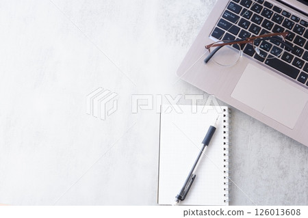 Image of doing desk work on a laptop while taking notes in a notebook 126013608