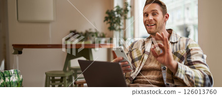 Portrait of man giving his positive feedback, shows okay, ok gesture, sitting with laptop. Cafe visitor approves good coworking space, holding mobile phone Portrait of man giving his positive feedback, shows okay, ok gesture, sitting with laptop. Cafe visitor approves good coworking space, holding mobile phone 126013760