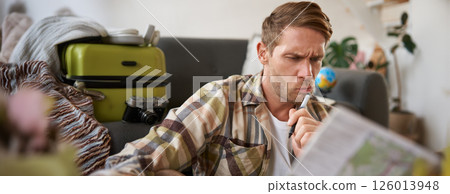 Man with confused face reads the map, traveller plans holiday, looks puzzled Man with confused face reads the map, traveller plans holiday, looks puzzled 126013948
