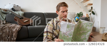 Portrait of man, traveller looks confused at map, studying the route to go on vacation or business trip 126014328