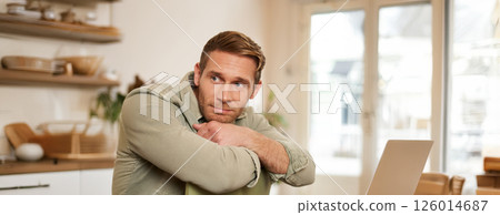 Vertical portrait of handsome masculine man, sitting on chair, looking aside, waiting for an order in coffee shop Vertical portrait of handsome masculine man, sitting on chair, looking aside, waiting for an order in coffee shop 126014687