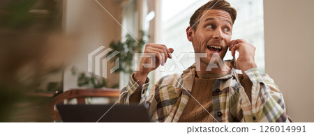 Freelance, digital nomad and workspace concept. Portrait of handsome young man with mobile phone, sitting in cafe with laptop, working on project, studying remotely, looking back outside window Freelance, digital nomad and workspace concept. Portrait of handsome young man with mobile phone, sitting in cafe with laptop, working on project, studying remotely, looking back outside window 126014991
