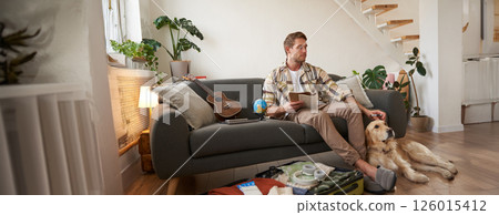 Portrait of man sitting with his dog, packing suitcase for a holiday, going on trip with a pet Portrait of man sitting with his dog, packing suitcase for a holiday, going on trip with a pet 126015412