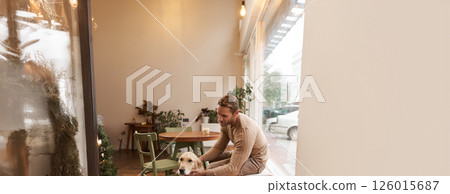 Handsome man sitting in cafe with his dog. A guy drinks coffee and strokes golden retriever. Animal-friendly coffeeshop Handsome man sitting in cafe with his dog. A guy drinks coffee and strokes golden retriever. Animal-friendly coffeeshop 126015687