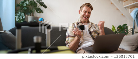 Portrait of man going on vacation, looking at his credit card, buying tickets online, booking hotel on website, preparing for holiday Portrait of man going on vacation, looking at his credit card, buying tickets online, booking hotel on website, preparing for holiday 126015701