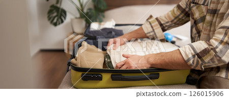 Male hands, tourist packing his clothes in luggage, putting items inside suitcase, getting ready for a vacation, going on holiday or business trip 126015906
