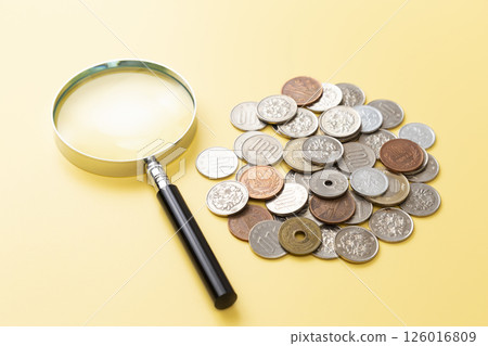 黃色背景中的硬幣和放大鏡 126016809