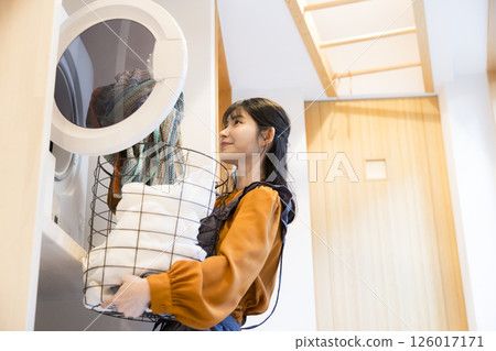 一位女士從滾筒洗衣機中取出衣物 一位女士從滾筒洗衣機中取出衣物 126017171