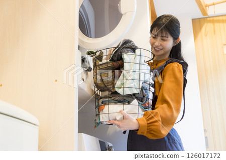 一位女士從滾筒洗衣機中取出衣物 一位女士從滾筒洗衣機中取出衣物 126017172