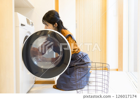 一位女士從滾筒洗衣機中取出衣物 126017174