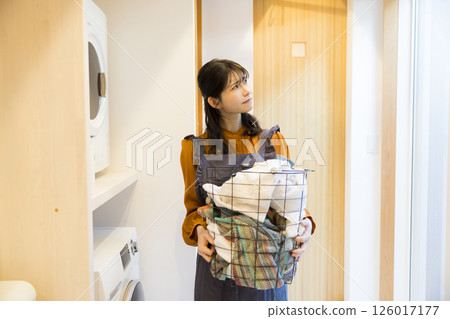 A woman taking laundry out of a drum washing machine 126017177
