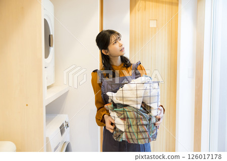 A woman taking laundry out of a drum washing machine A woman taking laundry out of a drum washing machine 126017178