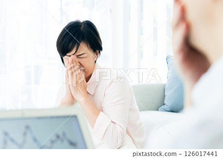 A middle-aged couple is shocked when looking at a computer in the living room 126017441