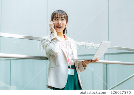 Businesswoman making a phone call with a laptop in the office Businesswoman making a phone call with a laptop in the office 126017570