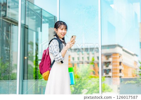 一位年輕的女大學生帶著智慧型手機 126017587
