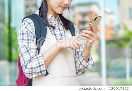 一位年輕的女大學生帶著智慧型手機 126017592