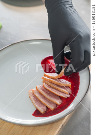 The chef places the duck on cranberry sauce. The chef places the duck on cranberry sauce. 126018181