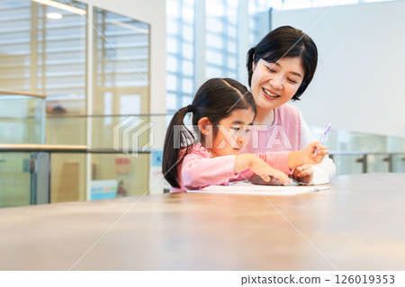 A girl studying and care staff watching over her 126019353