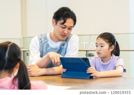 A girl looking at a tablet and a man teaching her how to use it A girl looking at a tablet and a man teaching her how to use it 126019355
