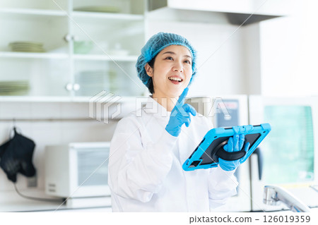 一名身穿衛生實驗服的女工正在檢查廚房 126019359