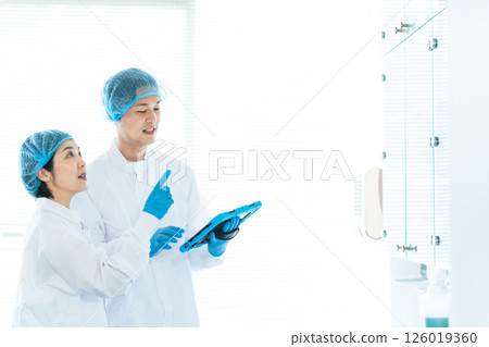 身穿衛生白大褂的男女工人檢查倉庫 126019360