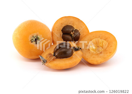 A close-up of fresh loquats, with some cut open to reveal their seeds and soft texture. 126019822