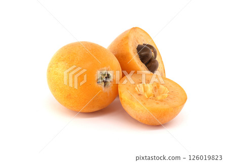 A collection of ripe loquats, with one cut to reveal the seeds, set on a bright white backdrop. 126019823